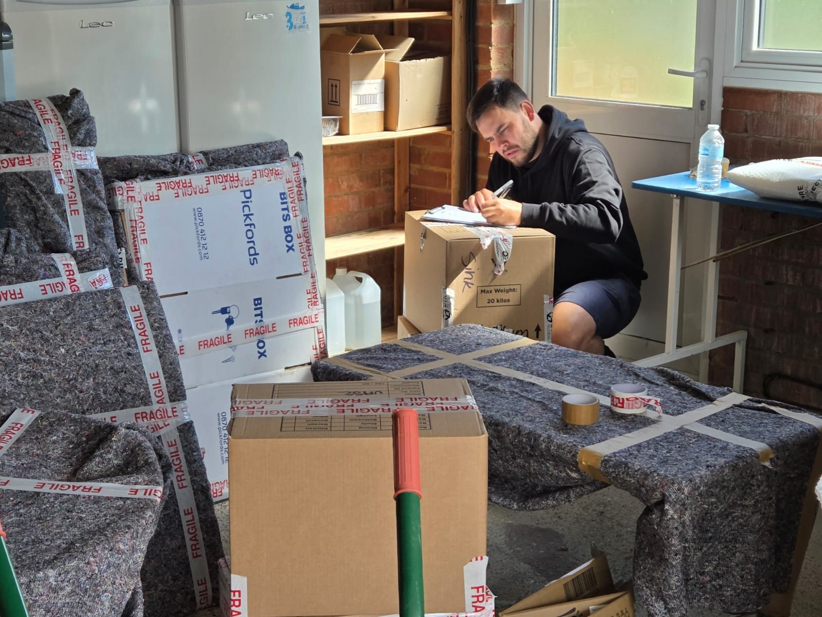 Recording details beside packed cartons and protected household items.