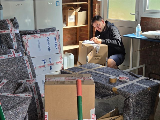 Recording details beside packed cartons and protected household items.